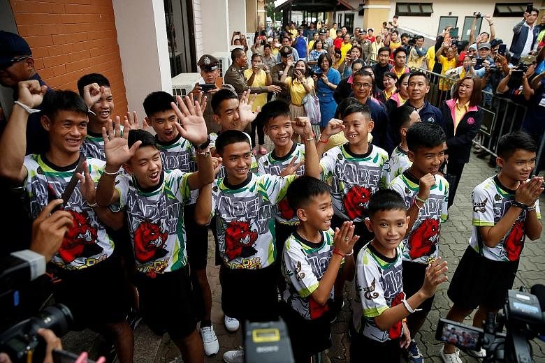 Crowds cheering as the 12 football players and their coach arrive for the news conference in the northern Thai province of Chiang Rai yesterday.