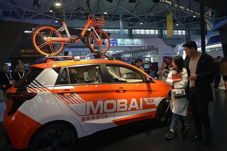 A shared vehicle and a shared bicycle of bike-sharing firm Mobike at the China International Big Data Industry Expo. Firms such as Mobike and ofo have hung on by winning the backing of China's biggest tech giants.