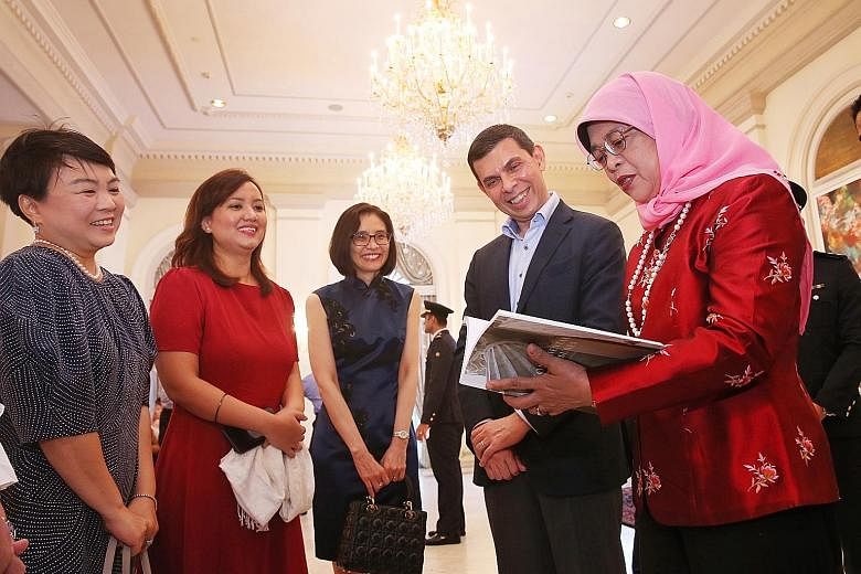 President Halimah Yacob taking a look at Monumental Treasures: Singapore's Heritage Icons with ST editor and ST Press chairman Warren Fernandez. With them are (from left) ST Press general manager Susan Long, book editor Melody Zaccheus and National H