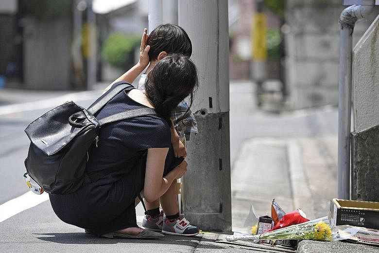 A woman and her child paying their respects outside the Tokyo apartment where five-year-old Yua Funato lived.