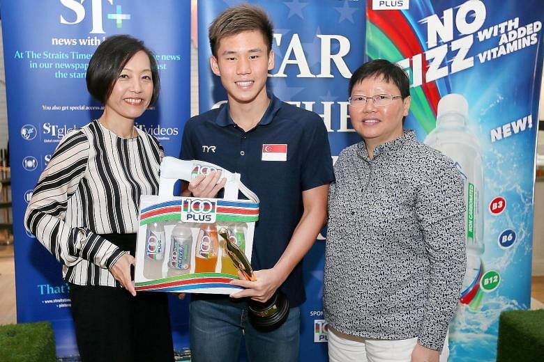 Jennifer See (far left), general manager of F&N Foods, and ST sports editor Lee Yulin, presenting national swimmer Glen Lim with his trophy and hamper.