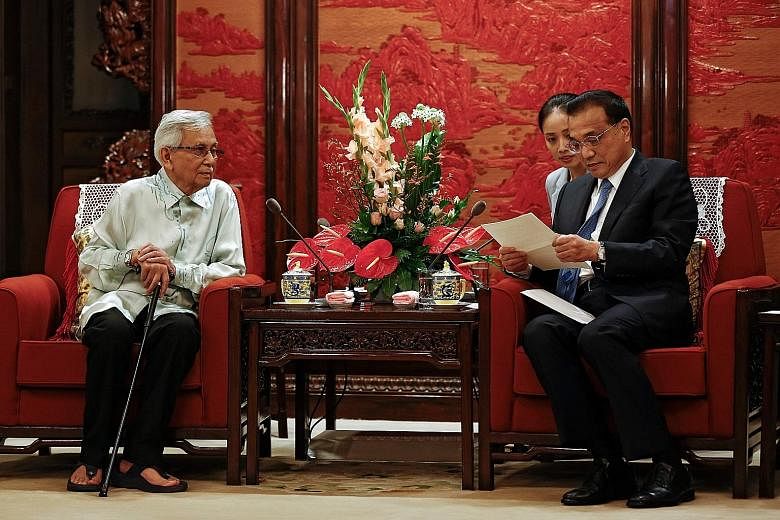 Chinese Premier Li Keqiang reads a letter from Malaysia's Prime Minister Mahathir Mohamad as Kuala Lumpur's special envoy Daim Zainuddin looks on at the Zhongnanhai Leadership Compound in Beijing last Wednesday. Mr Daim was in China to try and get ti