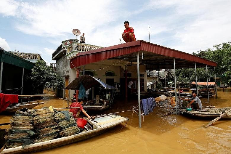 A man on the rooftop of his flooded house after heavy rainfall in Ninh Binh province, Vietnam, yesterday. Flash floods in Vietnam have claimed at least 19 lives, the government said.