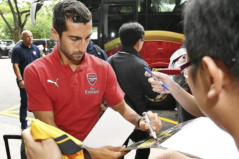 Above: Armenia midfielder Henrikh Mkhitaryan, who joined Arsenal from Manchester United in January, signing autographs. Right: A group of fans waiting for the Gunners to arrive at the Shangri-La hotel.