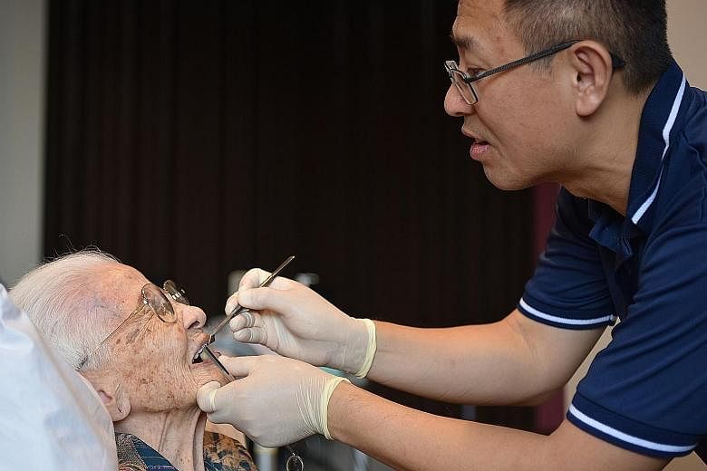 Madam Liew Yao Tai, 98, a resident of St Joseph's Home, having her dentures fitted by dentist Au Eong Kah Chuan, 50, on Sunday. He is among 20 dentists from the Humanitarian With Love group's dental section who visit the home once a month to provide 