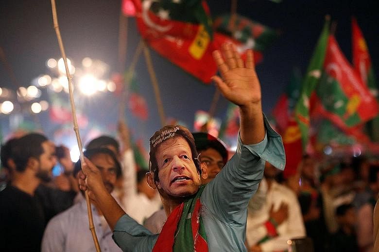 A supporter of Mr Imran Khan, wearing an "Imran Khan" mask during a campaign rally on Sunday ahead of today's general election in Karachi, Pakistan.