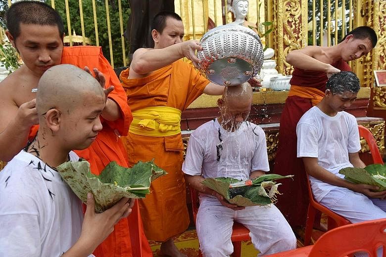 Buddhist monks shaving the hair of members of the "Wild Boars" football team at a Buddhist temple in the Mae Sai district of Chiang Rai province during a ceremony on Tuesday. Eleven of the 12 boys were ordained yesterday as novice Buddhist monks in m