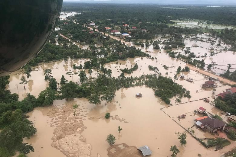 People affected by the flooding crowding around a Lao People's Liberation Army Air Force helicopter delivering relief supplies. An aerial view of the flooded area yesterday after a dam collapsed in Laos' remote Attapeu province on Monday.