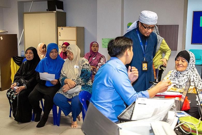 An-Nur Mosque manager Mohd Bahrul-Ulum Buang helping a senior citizen undergoing a medical consultation at the mosque with language translation. About 60 people went for the subsidised health screening on Wednesday.