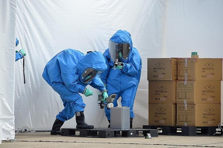 Japanese policemen in protective gear at the port of Yokosuka yesterday checking for mock chemical agents in a multinational drill aimed at preventing the proliferation of weapons of mass destruction.