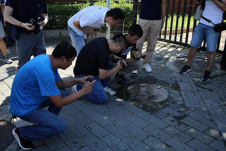 Reporters taking videos and photographs of a blood stain on the ground outside the US Embassy in Beijing following the blast yesterday. An image from a video posted on social media platform Weibo shows the scene immediately after the explosion outsid