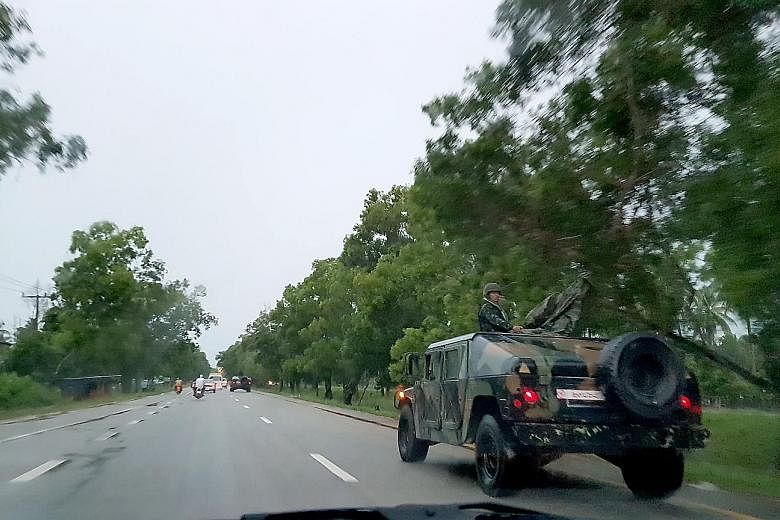Above: Soldiers in armoured vehicles on the highway to Betong in south Thailand. Left: Members of the National Defence Volunteers Organisation at a checkpoint in Sungai Kolok in Narathiwat province.