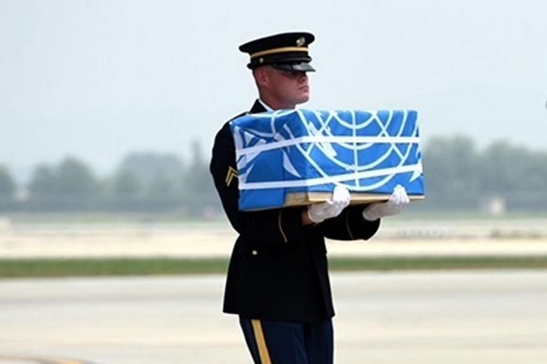A United Nations Honour Guard member carrying the remains of a US soldier at Osan Airbase yesterday. The return of the soldiers' remains marks the first tangible step in implementing a landmark agreement reached between the US and North Korea at the 