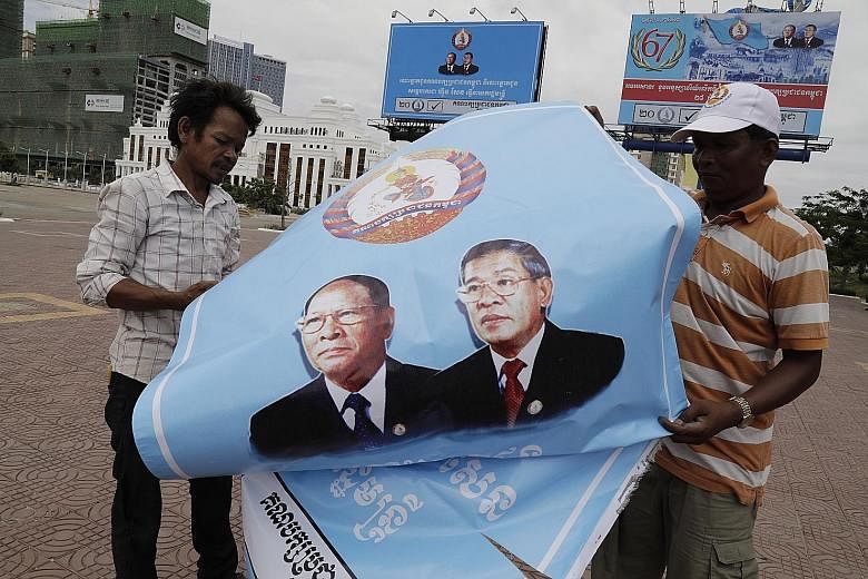 Cambodian workers folding a poster with portraits of Prime Minister Hun Sen (right) and President of the National Assembly Heng Samrin after the national elections in the country on Sunday.