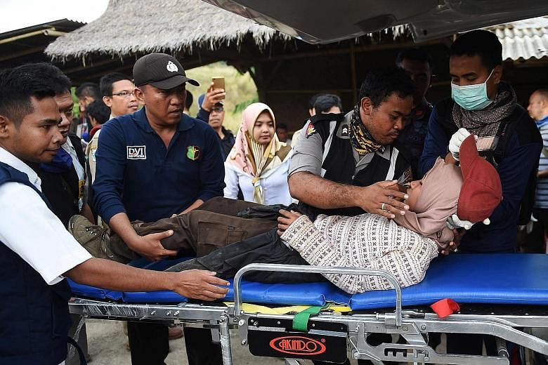 Rescue workers attending to an injured climber at Sembalun village in Lombok, Indonesia, yesterday, as their colleagues risked darkness, intermittent landslides and rockfalls to evacuate more than 560 people from Mount Rinjani following Sunday's 6.4-