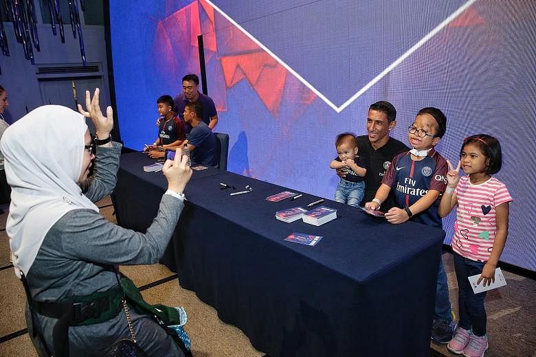 Juliana Mohamad taking a photograph of her children (from left) Muhd Firdaus Masli, Muhd Ridhwan and Nurin Insyirah with Paris Saint-Germain star Angel di Maria. His PSG team-mate Thiago Silva can also be seen at the meet-and-greet session held yeste