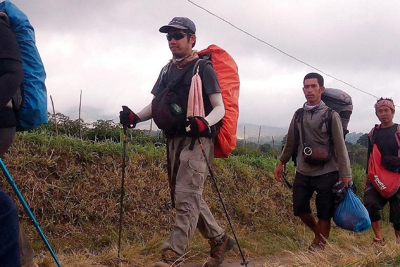Hikers (above) seen descending from Mount Rinjani on Monday in a photo released by the Indonesian military. More than 1,200 trekkers were trapped on the mountain when a quake struck Lombok on Sunday. Staff (below) at a morgue yesterday with a coffin 