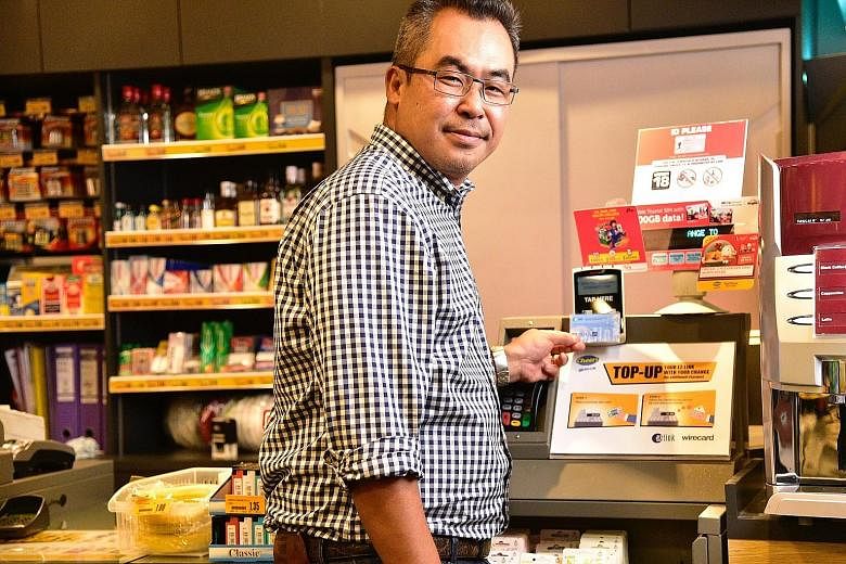 EZ-Link chief executive Nicholas Lee demonstrating how customers at Cheers convenience stores can use the change from their purchases to top up their ez-link cards. EZ-Link also aims to get users to migrate the monetary value stored on physical cards