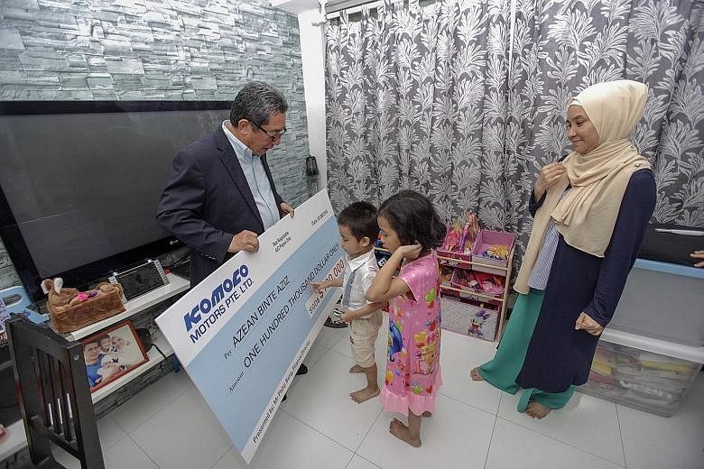Komoco Motors finance director Philip Beng presenting a cheque of $100,000 to Azean Aziz - the widow of former Woodlands Wellington footballer Nur Alam Shah Yusoff, who died of a heart attack in May - and two of her three children, son Muhammad Royya