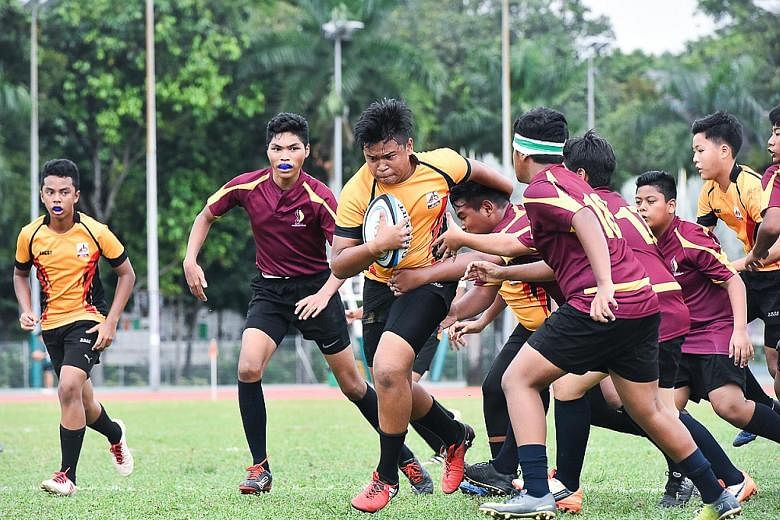 Bukit Batok Secondary's Muhammad Khaireel Aiman (with ball) breaking through Damai Secondary's defence line during their Schools National C Division Rugby Championship (Bowl) third-placing match on Wednesday. Bukit Batok won the match 35-22 to claim 