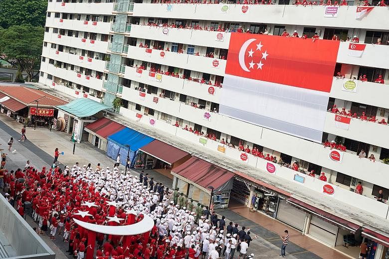 Bedok residents dressed in red and white form a human flag between Blocks 16 and 18 on Bedok South Road, mirroring a giant 12m-by-8m Singapore flag hung on the facade of Block 18. The block was also decorated with slogans such as Majulah Singapura as