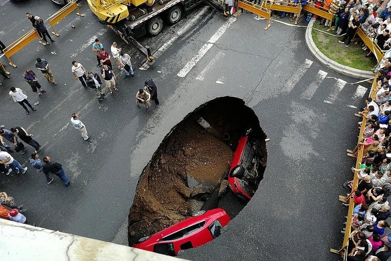 People gathering near the site where two vehicles had fallen into a sinkhole on a street in Harbin, capital city of Heilongjiang province in north-east China. The South China Morning Post reported yesterday that two cars plunged headfirst into the ho