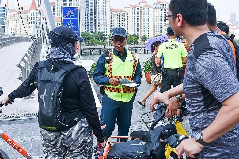 Auxiliary police officer Muhammad Hanafi Azeman, 27, sharing information on the Active Mobility Act with cyclists in Tanjong Rhu on Saturday. The officers are deployed alongside the Land Transport Authority's Active Mobility Enforcement Officers.