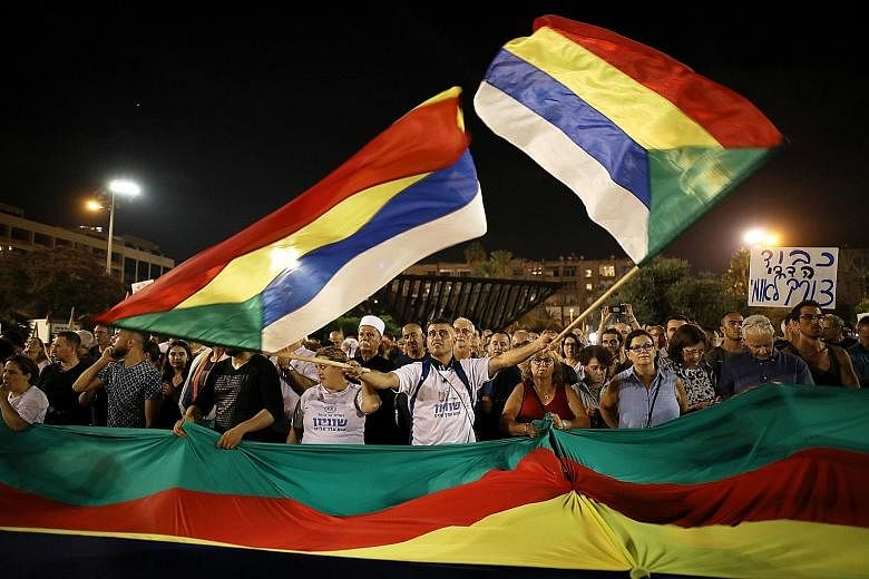 A protester waving the Druze community's flags in a rally against the Jewish nation-state law in Rabin Square in Tel Aviv last Saturday. Israel's prominent figures, including mayors and former chiefs of staff, have joined the protest.