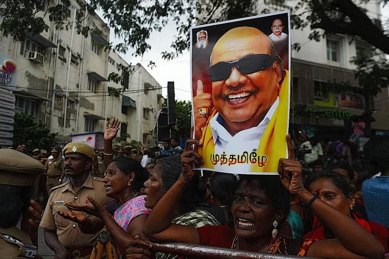 A Dravida Munnetra Kazhagam party supporter holding a portrait of party president M. Karunanidhi in front of the Chennai hospital where he died yesterday.