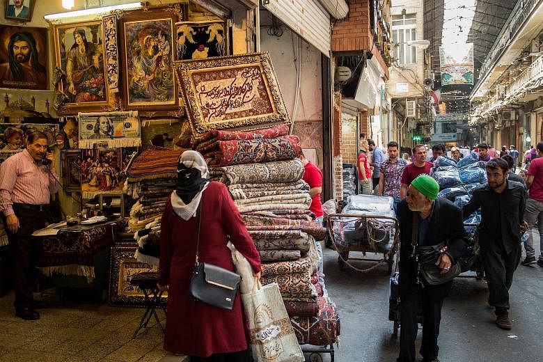 Carpet traders wheeling their wares past a store selling Persian rugs in Teheran's Grand Bazaar. Many Iranians blame their own government for the return of US sanctions, but they also fear it could be the "final nail in the coffin" for the flounderin