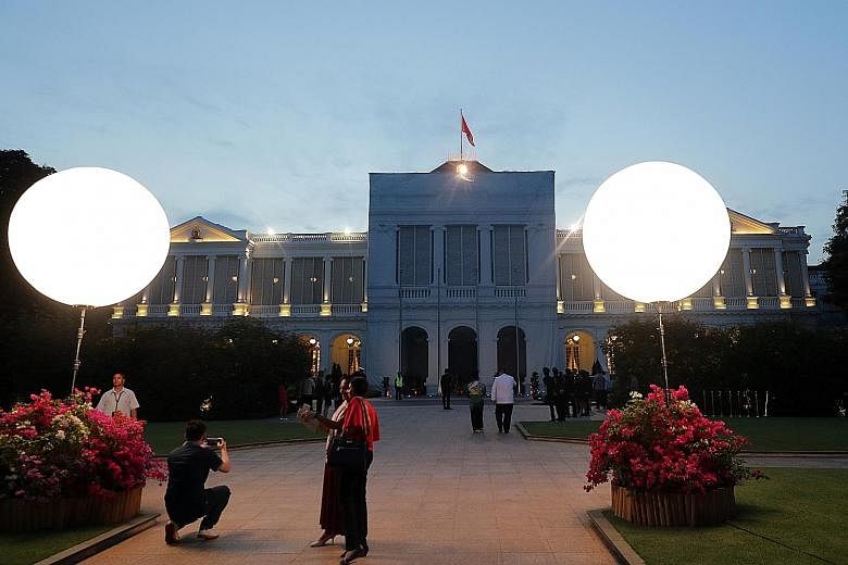 Left: Some 1,300 guests attended the National Day reception hosted by President Halimah at the Istana yesterday. Right: Guests snapping photos of the Istana before the start of the reception yesterday evening. From left: Mrs Lee, Prime Minister Lee H