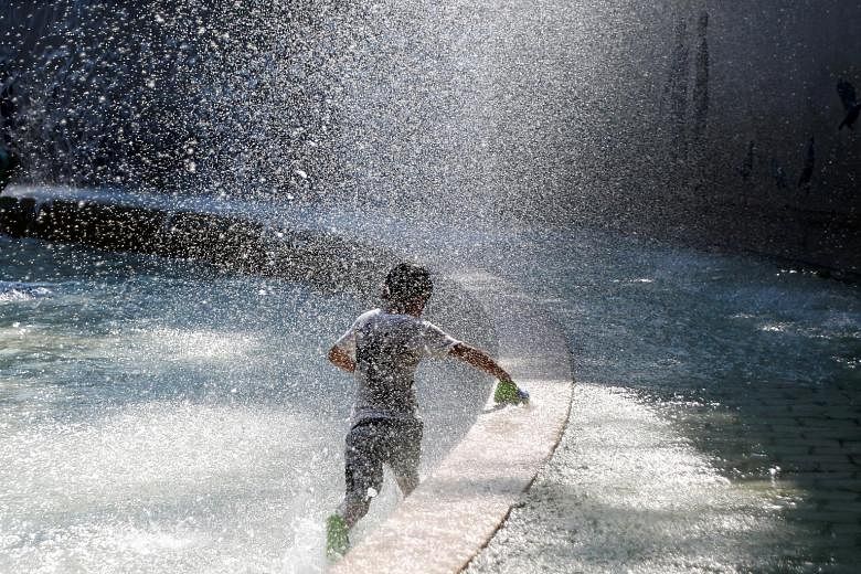 A firefighter (above) is seen battling a wildfire near Yosemite National Park in California in a US Forest Service photo released on social media on Monday. A boy (top) playing in a fountain to cool down at a park in Tokyo on Aug 1. In New South Wale