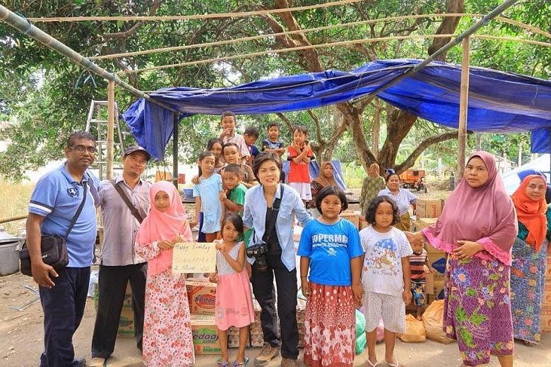 Singapore Red Cross volunteers Kamaraj Pandian (far left) and Lee Siew Yian (centre) with residents on Thursday in a village in West Lombok, where they are helping with relief efforts.