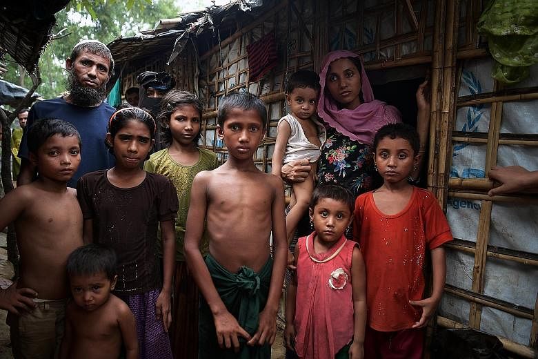 Madam Noor Beghum (right) with her four children and the man who took pity on them and took her family in to live together with his family, outside his home at the Kutupalong camp. Madam Beghum, who saw her husband hacked down, recounts how several s