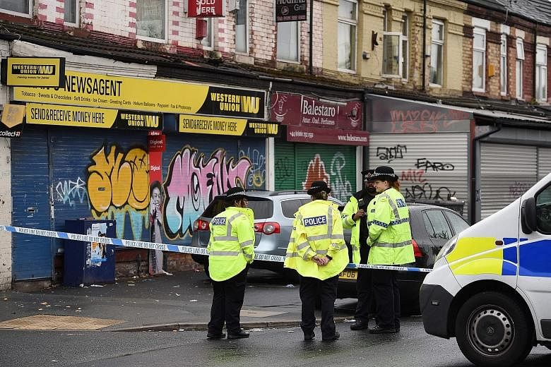 Police officers at the scene of the shooting in the Moss Side neighbourhood of Manchester, where 10 people were hurt.