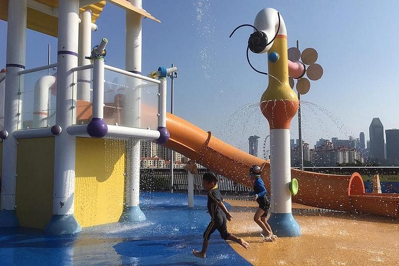 Above: Children cooling off at the water play area of the Singapore Sports Hub yesterday. Left: A tourist trying to keep cool in the searing heat in Chinatown yesterday.