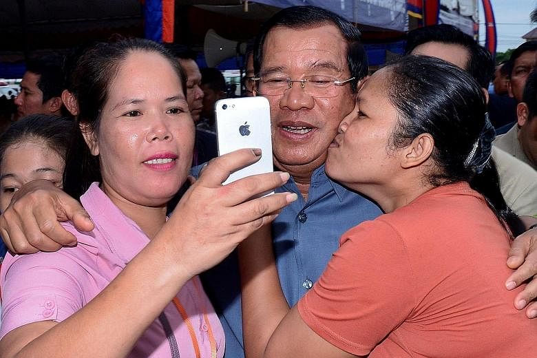 Cambodian Prime Minister Hun Sen (centre) posing with garment workers during a visit to a factory in Phnom Penh yesterday. In a statement, the National Election Committee confirmed yesterday that his Cambodian People's Party had won all 125 parliamen