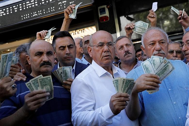 Businessmen holding US dollars in front of a currency exchange office in Ankara on Tuesday, after Turkish President Recep Tayyip Erdogan called on Turkish citizens to sell their dollar and euro savings to support the lira.