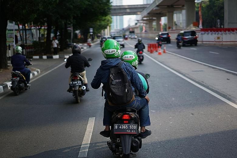 A Go-Jek motorcycle taxi driver with a passenger on the road in Jakarta. The ride-hailing firm, which began operating in Indonesia in 2011, said it is in talks with the Competition and Consumer Commission of Singapore and "has not commenced any drive