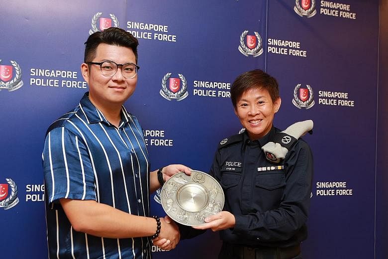 Engineer Goh Tong En receiving his award from Deputy Assistant Commissioner of Police Evon Ng yesterday. He was commended for preventing a man from taking upskirt videos on an escalator at Marsiling MRT station last month.