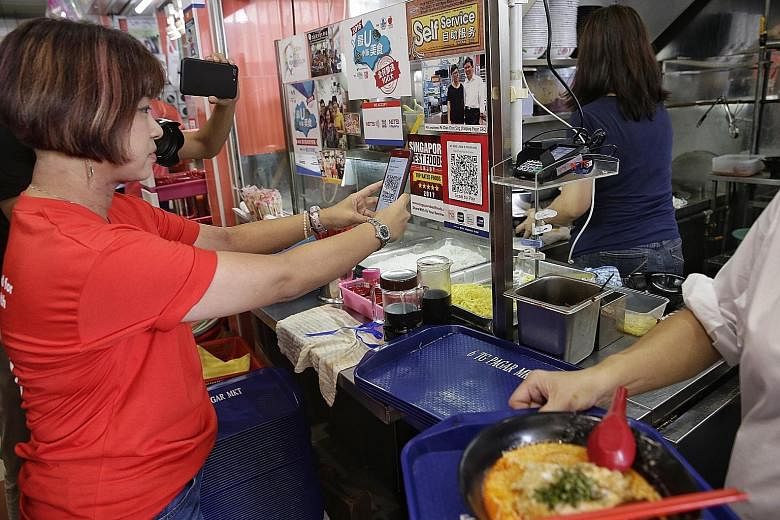 A patron making a purchase by scanning a QR code at Tanjong Pagar Plaza Market and Food Centre. The Singapore authorities will create a unified e-payment system at all 12,000 stalls in hawker centres, which is expected to lower transaction fees and s
