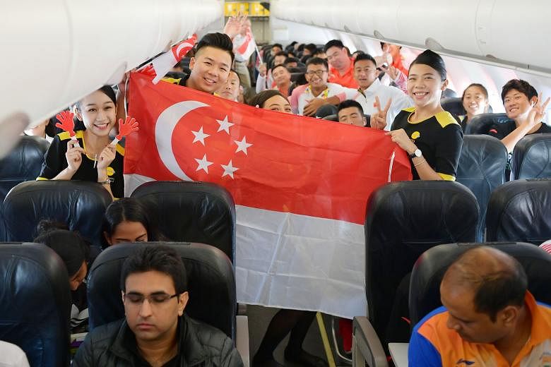 Above: Students posing with one-horned rhino Kaka, one of the mascots, outside Gelora Sriwijaya Stadium, the main venue in the Asian Games co-hosting city Palembang. Left: Scoot cabin crew holding the Singapore flag before departing for Palembang wit