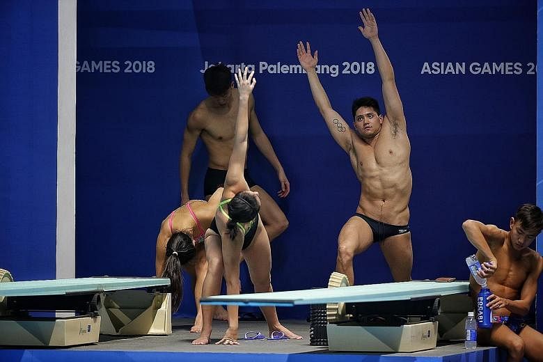 Olympic 100m butterfly gold medallist Joseph Schooling stretching with his Singapore team-mates during training at the Gelora Bung Karno Aquatic Centre in Jakarta yesterday.