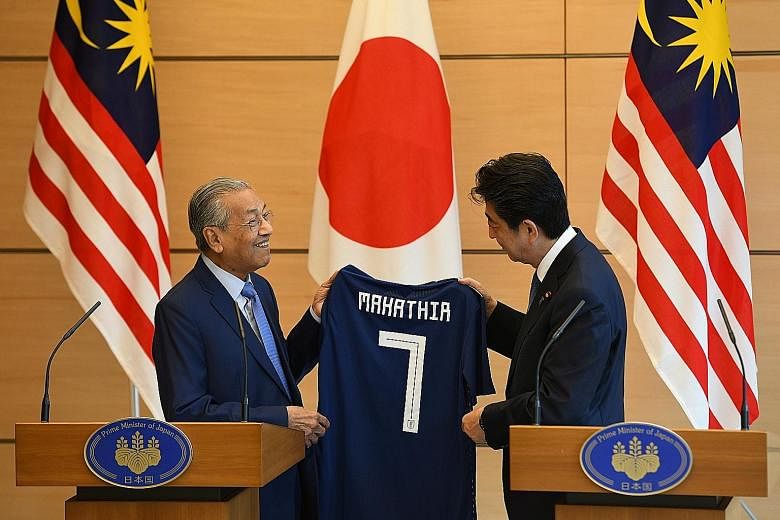 Dr Mahathir inspecting a newly launched Proton Waja in Shah Alam, Malaysia, in 2000. Dr Mahathir receiving a Japanese national football jersey from his Japanese counterpart, Mr Shinzo Abe, in Tokyo in June. Dr Mahathir wants to increase Malaysia's pr