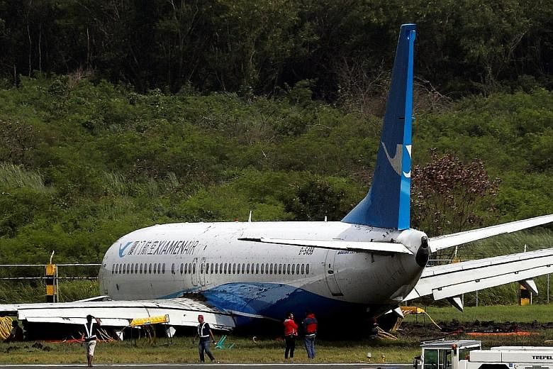 The Xiamen Air plane on the tarmac yesterday after skidding off the runway at Manila's Ninoy Aquino International Airport late on Thursday. Its left engine was ripped off (top left) during the incident.