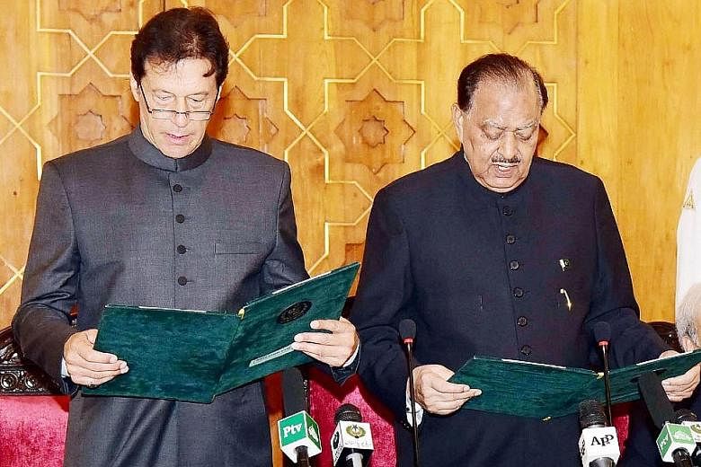 Pakistan's new Prime Minister Imran Khan, with President Mamnoon Hussain (far right) beside him, reciting the oath of office in Islamabad yesterday.