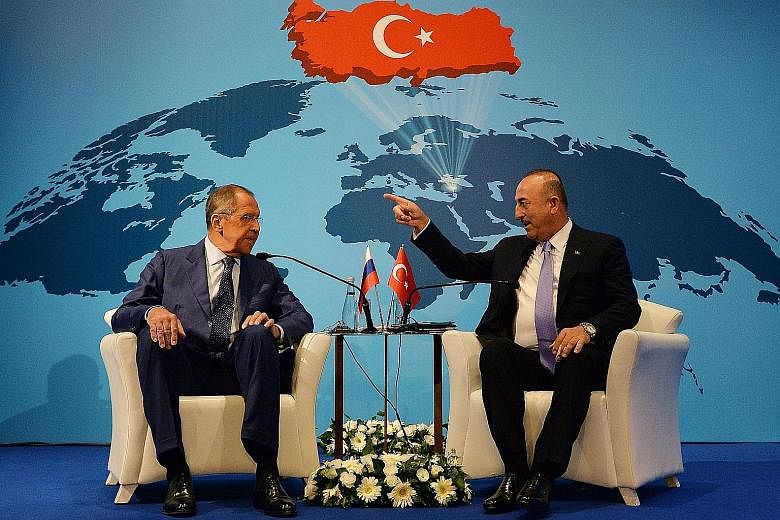 Russian Foreign Minister Sergey Lavrov (far left) meeting his Turkish counterpart Mevlut Cavusoglu in Ankara on Tuesday. Both countries are drawing closer to each other largely because of the US imposing sanctions on them, says the writer.