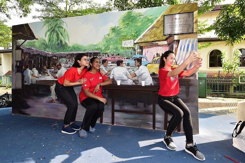Yishun Community Hospital nurses (from left) Nur Rafiqah, 21, Saroja Muniandy, 55, and Wendy Yew, 22, who also took part in a litter-picking exercise, posing for a wefie at the newly launched mural which depicts what the area looked like in the 1960s