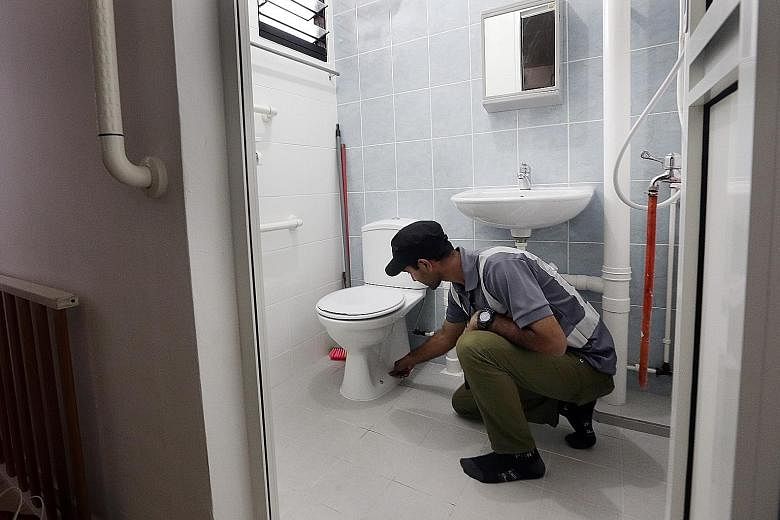 Above: A supervisor inspecting a toilet with elder-friendly features installed under the Enhancement for Active Seniors programme, which is part of the Home Improvement Programme (HIP). Left: A supervisor inspecting the gate of a Jurong flat under th
