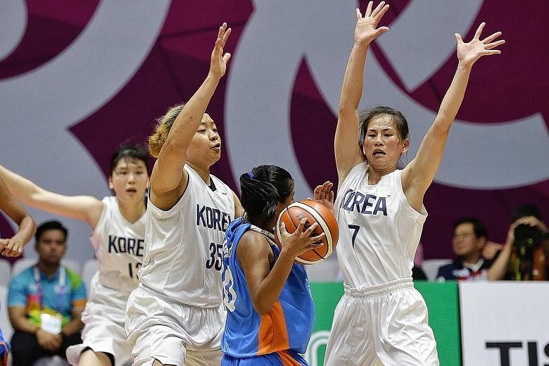 Unified Korea's Jang Mi Gyong (right, a North Korean) and team-mate Kim Han-byul, from the South, defending against India's Madhu Kumari in the women's basketball preliminary Group A match. The Koreans won 104-54.